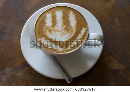 A cup of latte art coffee on wooden background