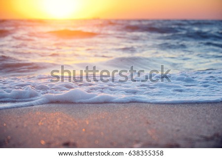 Soft wave of sea on sandy beach at warm gold sunset light. Selective focus.