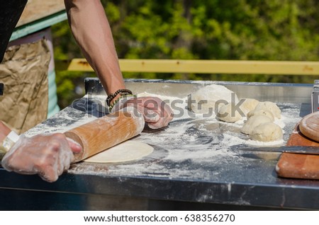 The chef at the fair rolls out the dough to make Italian piadins.