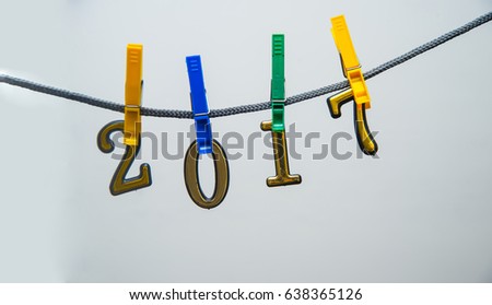 The word 2017 spelled out on colorful plastic clothespin clipped metal golden numbers in front. isolated on white or gray background