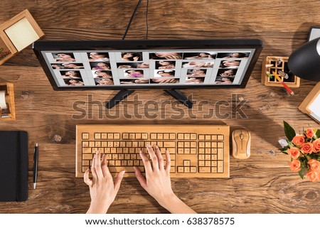 Female Designer Using Wooden Keyboard With Set Of Women's Picture On Computer Screen