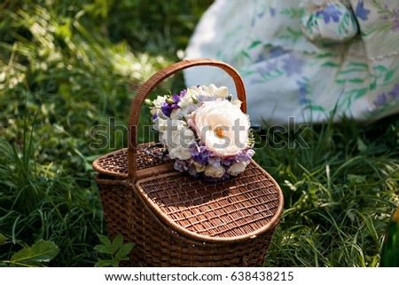 Romance, love, valentine's day concept - wicker basket with bouquet of flowers, bottle wine on the grass. Spring fresh sunny background