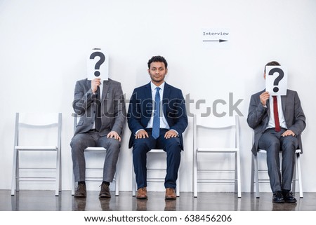 businesspeople sitting in queue and waiting for interview, holding question marks in office, business concept