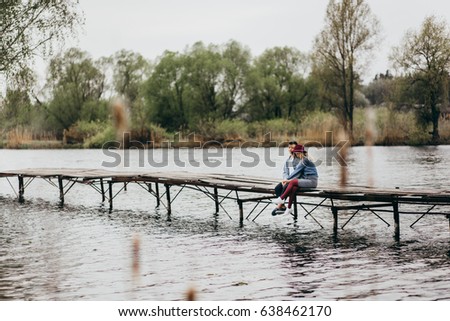 Couple are  sitting on the long bridge near the lake