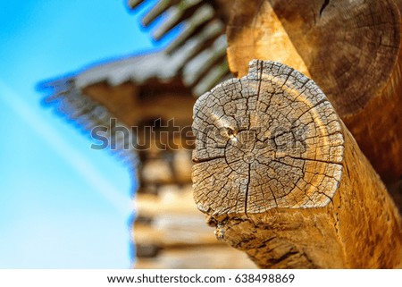 Details of log cabin corner joint with round logs and blurry roof of wooden house on the background at sunny spring day, Moscow, Russia