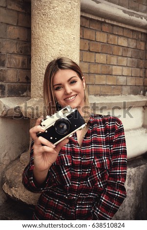 Girl smiling and holding retro camera outdoor