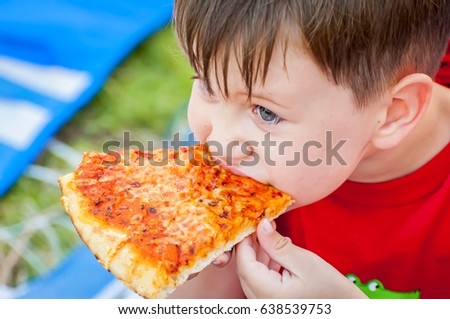 Cute little kid taking a bite from a delicious margarita pizza slice. Pizza recipe.