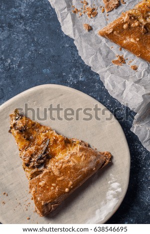 Piece of cut leek and onion galette with sage and gruyere cheese made with wholegrain flour. Textured blue background. Rustic concept 