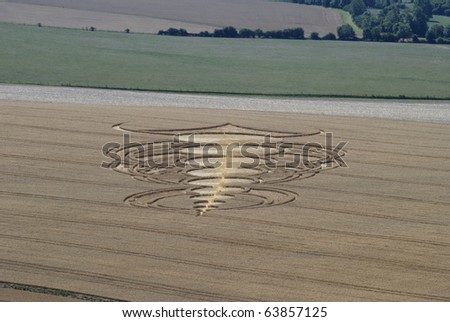 Crop circle in middle of corn field below Pewsey Downs near Avebury. Wiltshire. England Royalty-Free Stock Photo #63857125