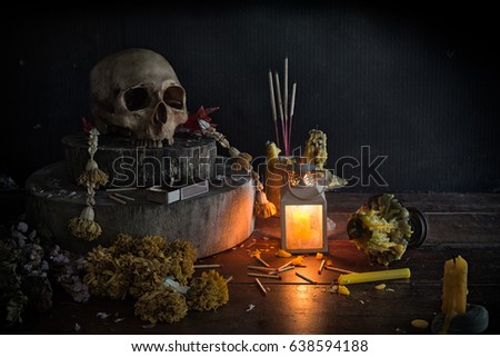 Skull on altar and candle with incense have bright by lantern light / Still life and selective focus

