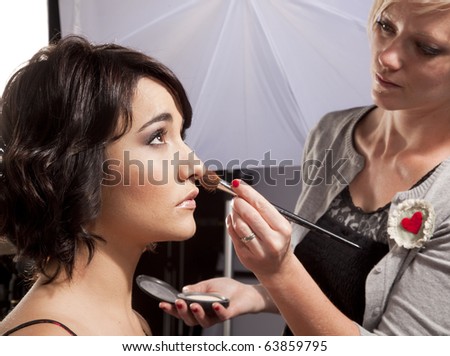 Makeup artist applying makeup to a model at a photo shoot.