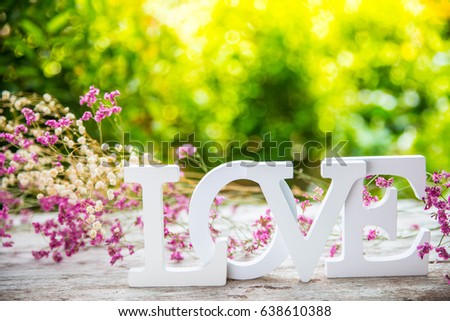 White LOVE  character with nature background and dry flower around , soft focus and bokeh