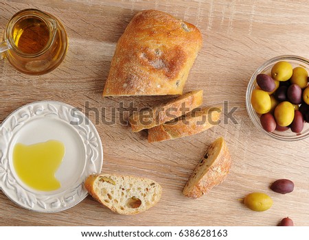 ciabatta with olives and yellow and purple olives with black olives, olive oil on wooden background - top view