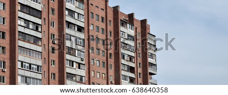 Photo of an old brick multi-storey apartment house in a poorly-developed region of Ukraine or Russia. Obsolete multi-storey building (hostel) against the background of a cloudy sky