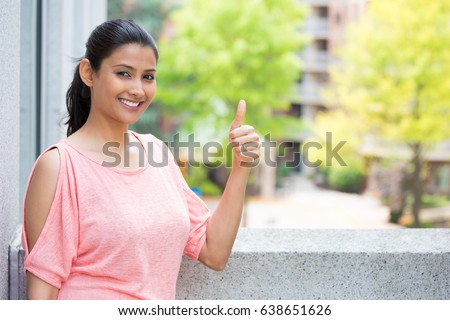 Closeup portrait of young pretty woman in pink shirt with two thumbs up sign gesture, isolated outdoors background. Positive emotion facial expression feelings, signs and symbols, body language Royalty-Free Stock Photo #638651626