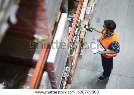 Worker with scanner making review of goods in warehouse Royalty-Free Stock Photo #638769808