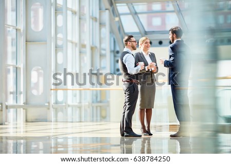 Group of modern business people chatting during coffee break  standing in sunlit glass hall of office building Royalty-Free Stock Photo #638784250