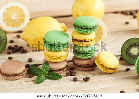 Green, yellow and brown french macarons with kiwi coffee beans and mint decorations, soft focus background
