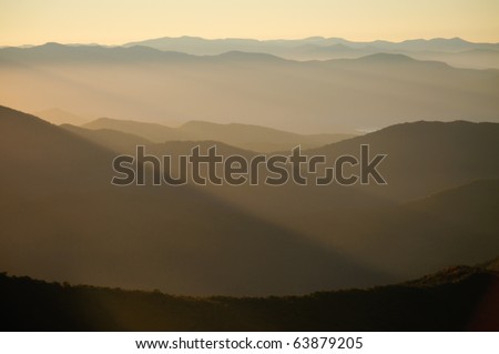 yellow rays shining over mountains at sunrise