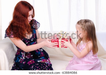 Little girl mom gives a holiday gift in red box with white ribbon.