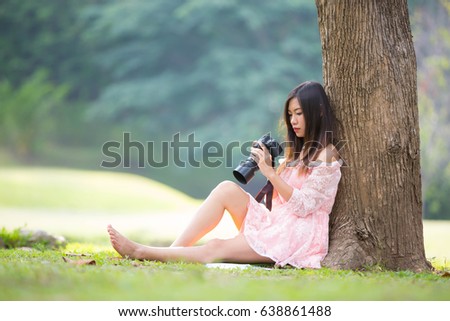 The girl is viewing a photo from a camera in a park.