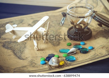 Toy wooden plane on a world map with colored stones and shells from the sea in a retro style. Concept of travel, discovery and exploration of new