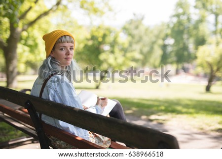 Young woman sat writing a note in the park