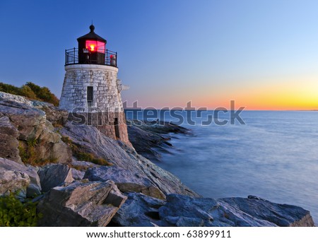 Beautiful lighthouse by the ocean at sunset Royalty-Free Stock Photo #63899911