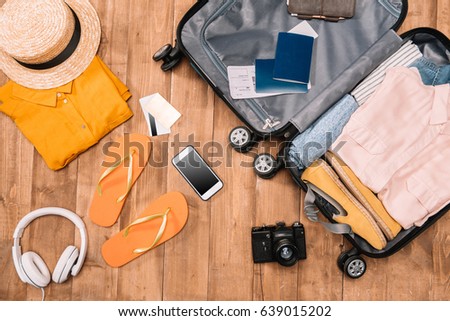 Ready for travel concept. Top view of essentials for tourist with clothes, accessories and gadgets, wallet, passport, smartphone in bag.  