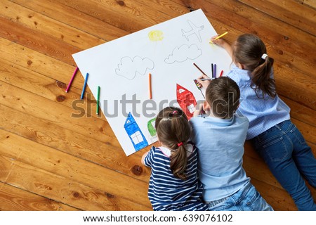 Happy children. Top view creative photo of little boy and girl on brown wooden floor. children draw together on a large sheet of paper
