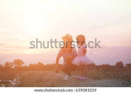 Mother encouraged her daughter out of the shadows at sunset.