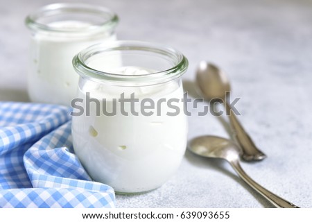 Two portions of fresh natural  homemade organic yogurt in a glass jar on a light slate background. Royalty-Free Stock Photo #639093655