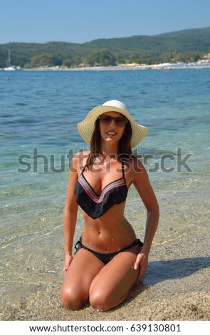 Beautiful young woman in bikini on the sunny beach relaxing 