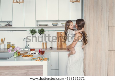 Mom and daughter in the kitchen. Daughter hugging mother on the kitchen. Royalty-Free Stock Photo #639131371