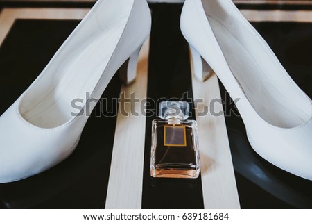 White bride shoes and perfume bottle on the table with stripes, stylish geometry