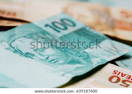 Macro closeup of a 100 Brazilian reais banknote on 50 reais notes on background