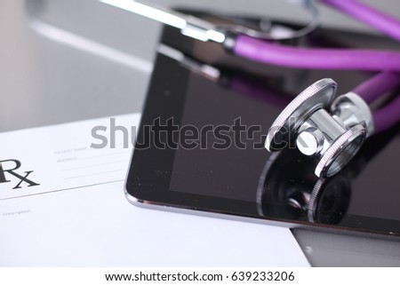 Tablet computer with a stethoscope lie on a table