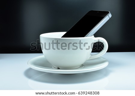 The smartphone is in the coffee mug. The Concept- Some people like to use a smartphone and drink coffee simultaneously.