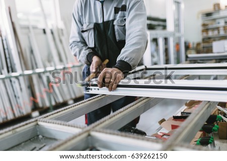 Factory for aluminum and PVC windows and doors production. Manual worker assembling PVC doors and windows. Selective focus.  Royalty-Free Stock Photo #639262150