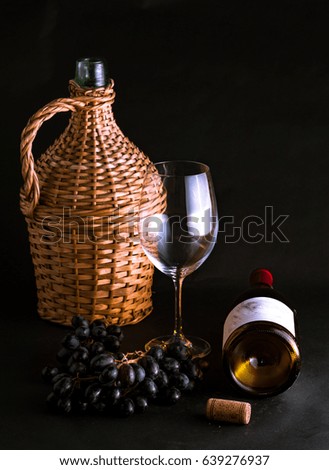 Glass, bottle of red wine with a cluster of grapes