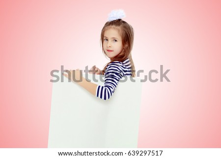 The little blonde girl with long hair and with a white bow on her head , in a blue striped summer dress.She peeks out from behind white banner.Pale pink gradient background.