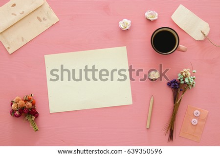 vintage mockup with flowers, cup of coffee and blank letter on pink wooden background