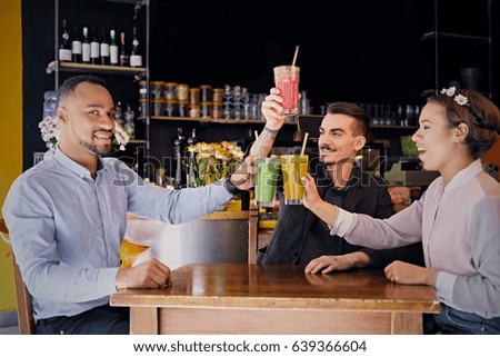 Black American and Caucasian friends drinks refreshment vegan coctails in a restaurant.