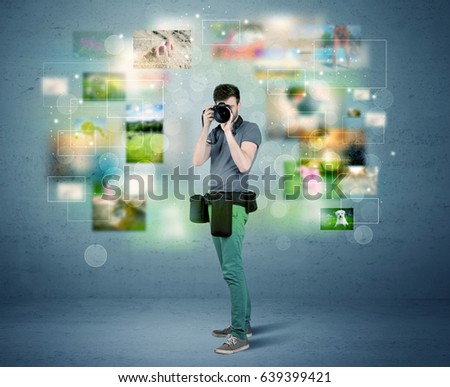 A young amateur photographer with professional camera equipment taking picture in front of blue wall full of faded pictures and glowing lights concept