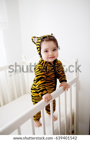Cute baby wearing a tiny tiger costume. Having fun in her crib. Royalty-Free Stock Photo #639401542