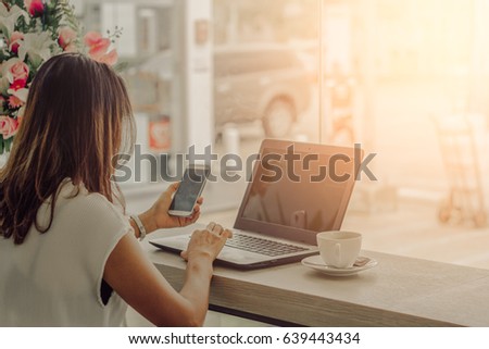 Laptop and coffee cup in girl's hands sitting on a wooden floor / soft focus picture / Vintage concept