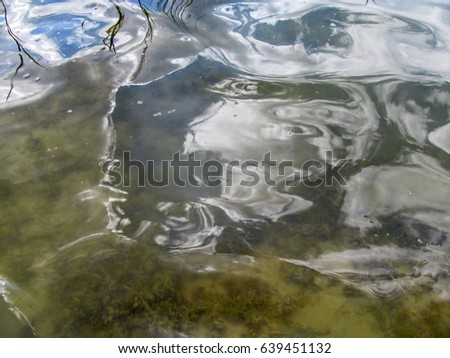 Abstract beige blue water background. Through the water you can see the sandy bottom with algae And the reflection of the sky on the surface