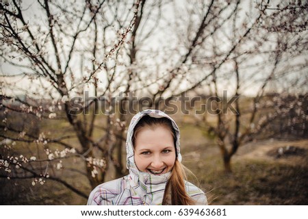 Happy girl with brackets on the teeth, Braces. Standing in field. Appear kidney leaves and flowers on young tree. beautiful spring landscape: the branches, trunk of birch with Blossoming buds, nature