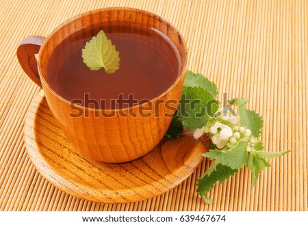 Wooden cup of nettle tea  on bamboo background