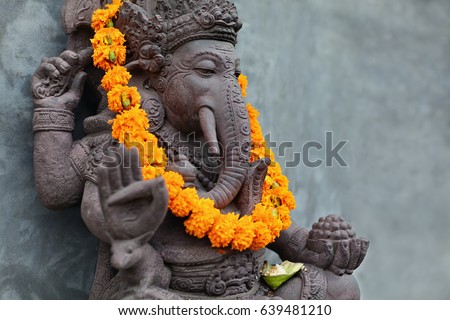 Ganesha with balinese Barong masks sitting on front of temple. Decorated for religious festival by orange flowers necklace and ceremonial offering. Travel background, Bali island art and culture. Royalty-Free Stock Photo #639481210